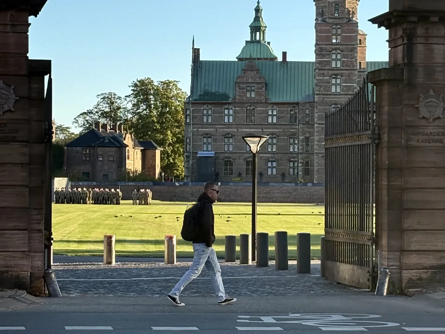 Mand går forbi en kasserneport, mens soldater stiller op foran et renæssanceslot.